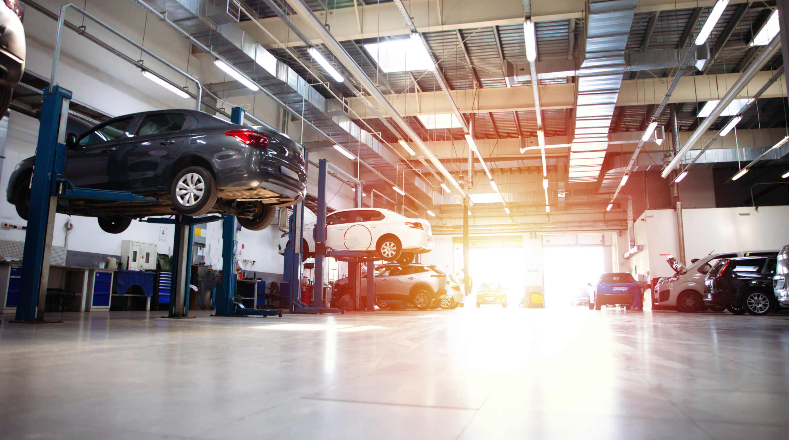 Modern car repair station with multiple vehicle lifts and specialized diagnostic equipment, illustrating the operational environment of Merlin Complete Auto Care.
