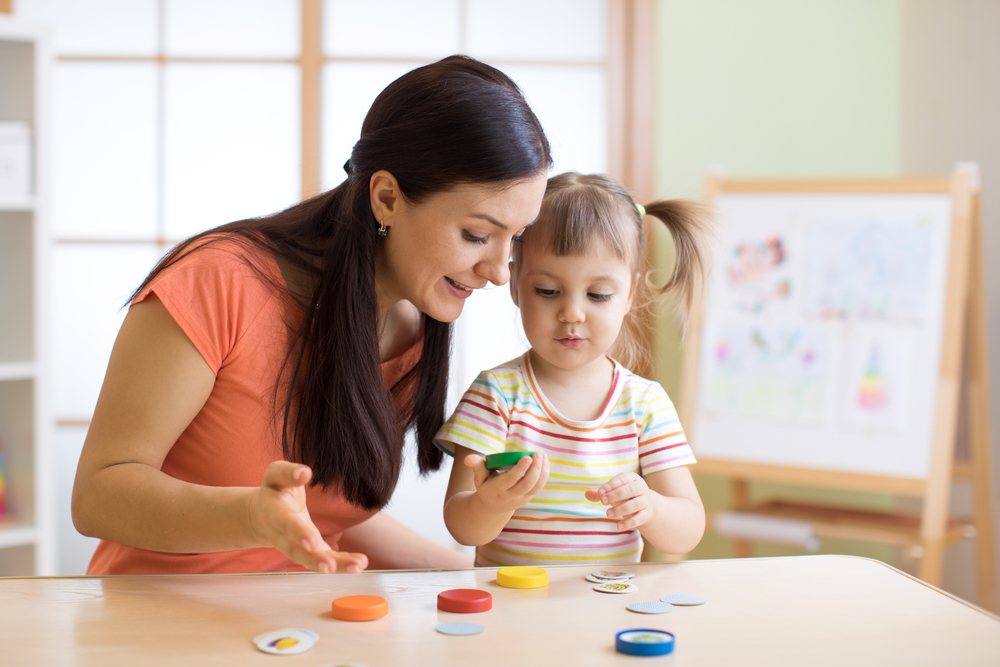 Mother and child engaging in educational play with colorful learning materials in a child care setting.