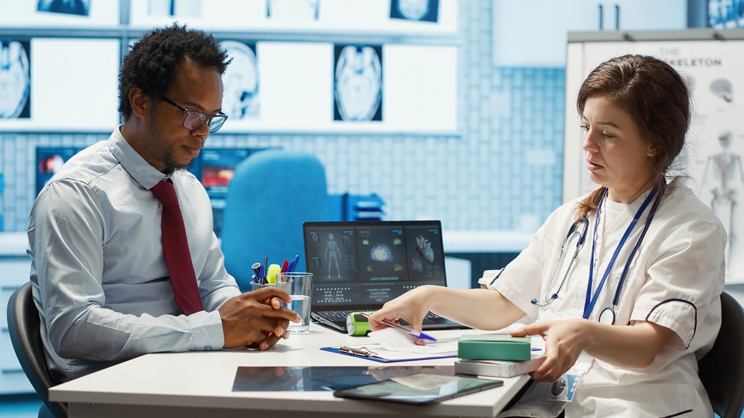 Doctor consulting patient in healthcare office, discussing treatment options with medical equipment and documents on the table, relevant to Actinium Healthcare Holdings' services.